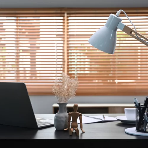 computer-laptop-supplies-and-white-lamp-on-black An office desk with window blinds at the back.